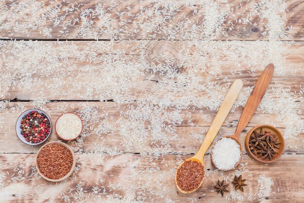 Brown and white rice with dry spices on textured background