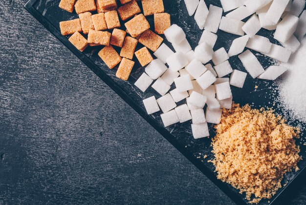 Brown and white sugar in a cutting board. top view. copy