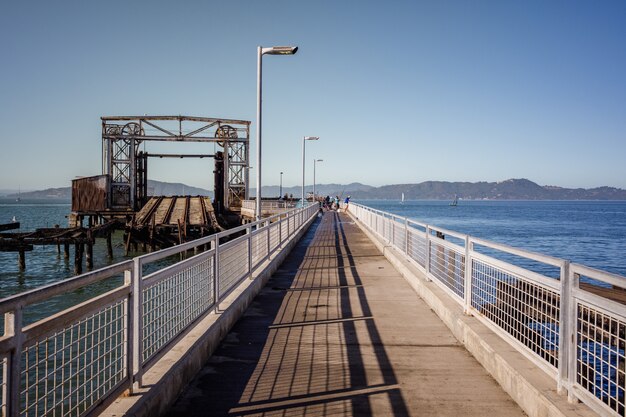 Коричневый деревянный мост через синее море под голубым небом в дневное время