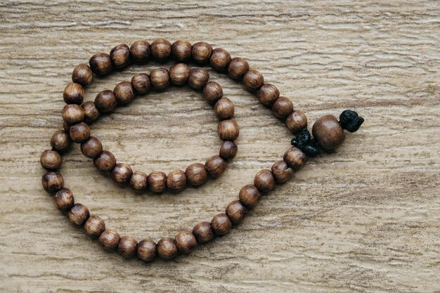 Brown wooden prayer rosary on a wooden background. top view. copy, empty space for text