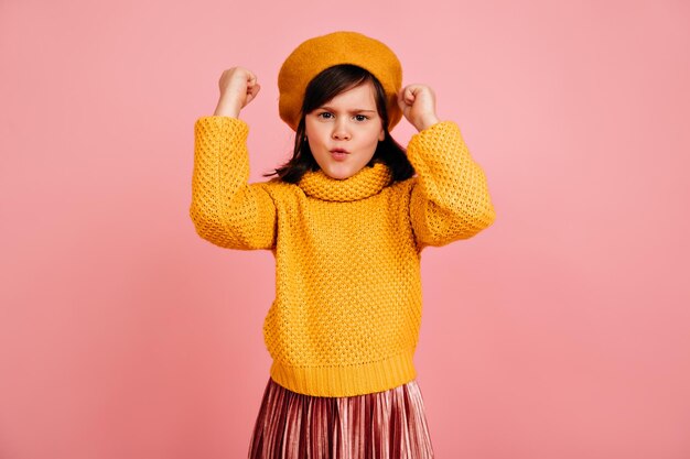 Brownhaired kid waving fists Studio shot of emotional child in yellow attire