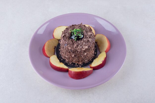 Brownie cake and sliced apples on plate on marble table.