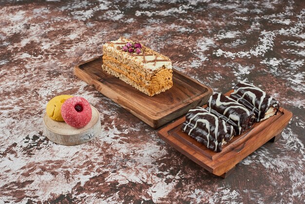 Brownies and a slice of cake on a piece of wood.