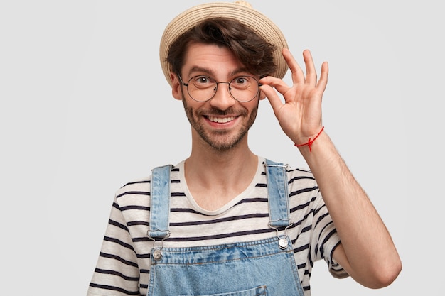 Free photo brunet man wearing hat and denim overalls