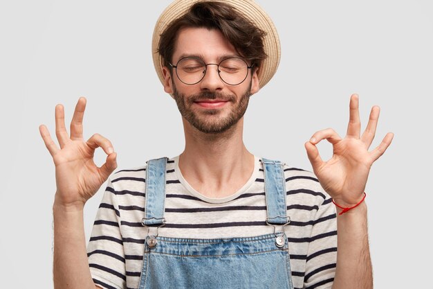 Brunet man wearing hat and denim overalls