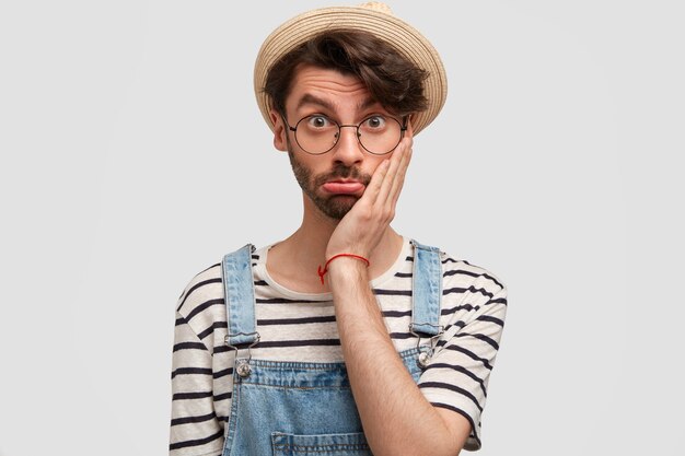 Brunet man wearing hat and denim overalls