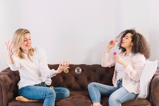 Brunette blowing bubbles near friend