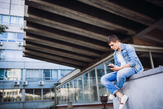 Free photo brunette boy in jeans jacket poses outside