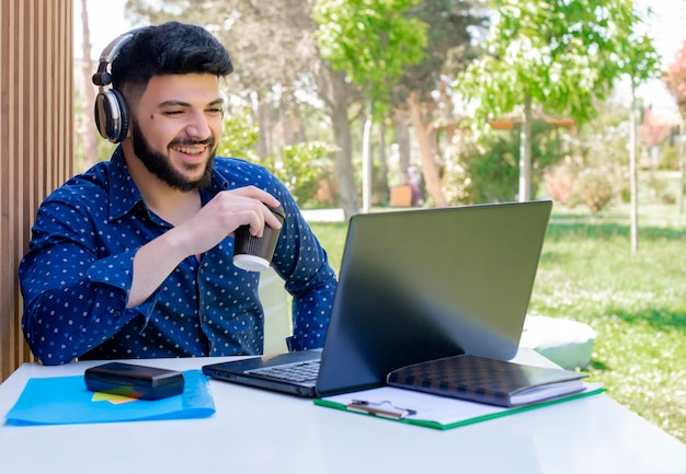 Brunette boy listening to music in earphones working outdoors