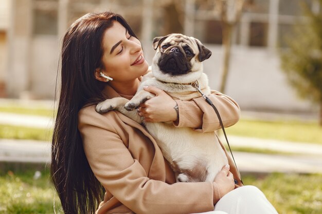 Brunette in a brown coat walks with pug