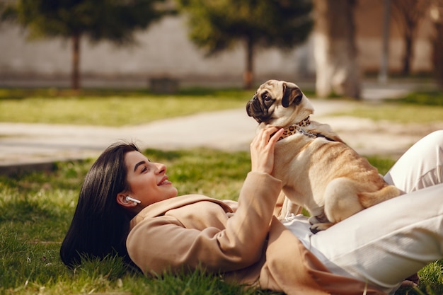 Brunette in a brown coat walks with pug