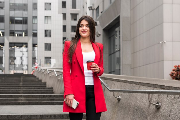 Brunette businesswoman outdoors with read coat