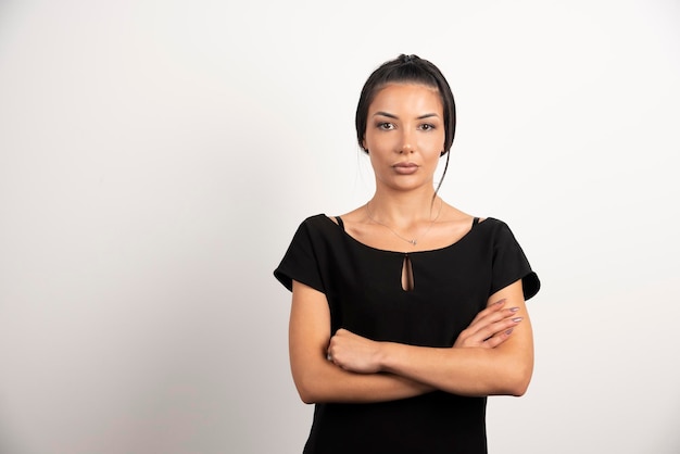 Brunette businesswoman standing on white wall.