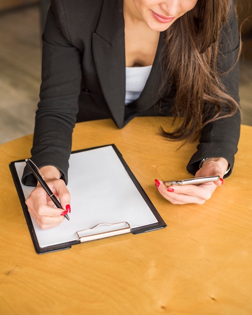 Free photo brunette businesswoman writing on a document