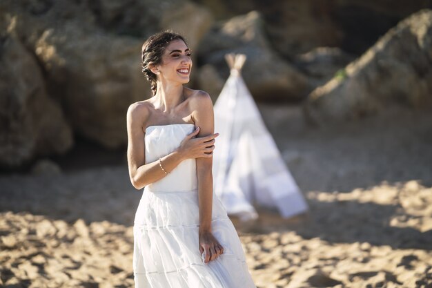 Brunette caucasian bride smiling while posing at the beach