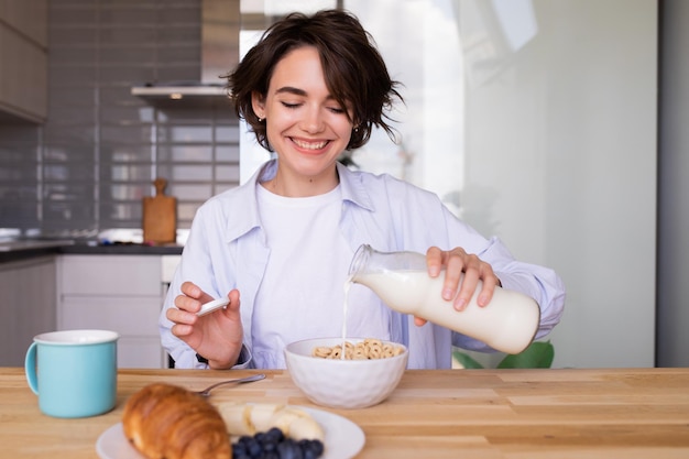 Foto gratuita donna caucasica castana che fa colazione a casa