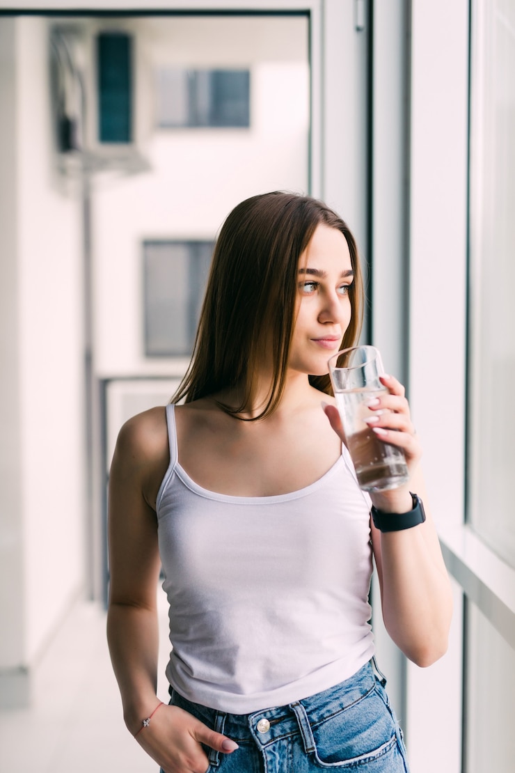 Free Photo brunette drinking water in the living room at home