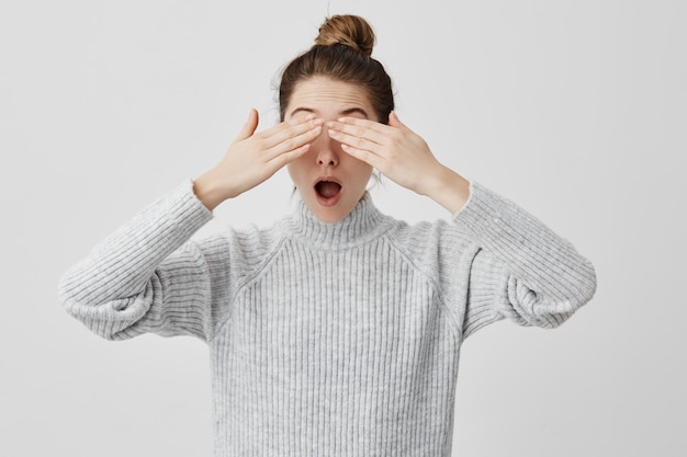 Brunette female 30s covering eyes with hands standing with open mouth. Young woman being hit with news not want to see reality. Emotions concept