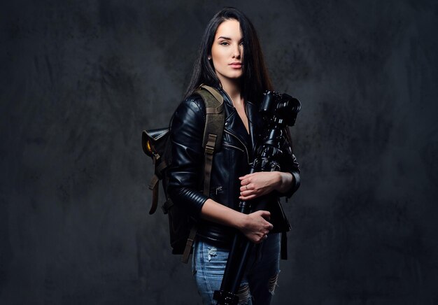 Brunette female photographer holds professional camera on a tripod and traveler backpack.