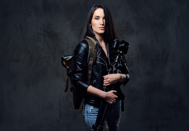 Brunette female photographer holds professional camera on a tripod and traveler backpack.