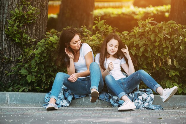 Brunette females sitting on pavement curb