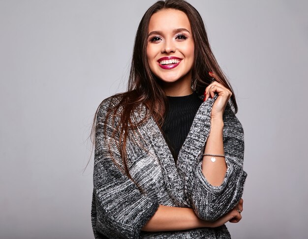 brunette girl in casual warm sweater clothes on gray with evening makeup and colorful lips