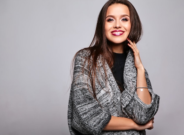 brunette girl in casual warm sweater clothes on gray with evening makeup and colorful lips