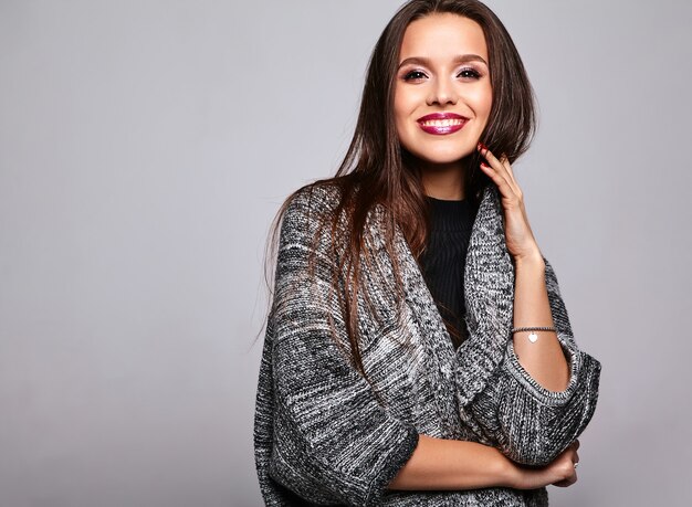 brunette girl in casual warm sweater clothes on gray with evening makeup and colorful lips