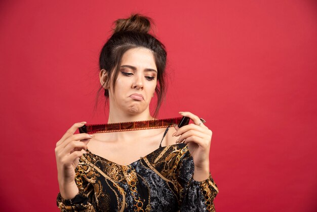 Brunette girl checks her photo history on polaroid film and looks dissatisfied. 