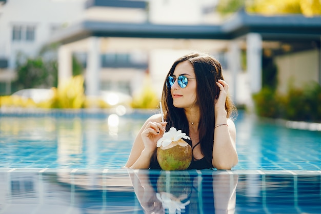 Brunette girl eating fruit by the pool