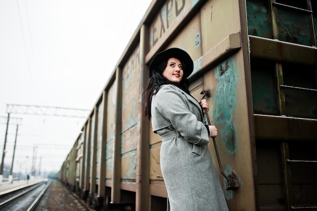 Brunette girl in gray coat with hat in railway station