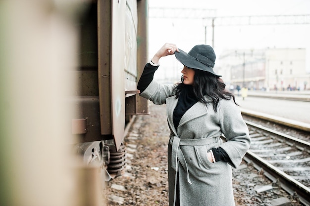 鉄道駅で帽子とグレーのコートでブルネットの少女