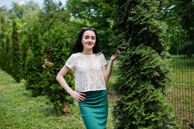 Free photo brunette girl in green skirt and white blouse posed at park