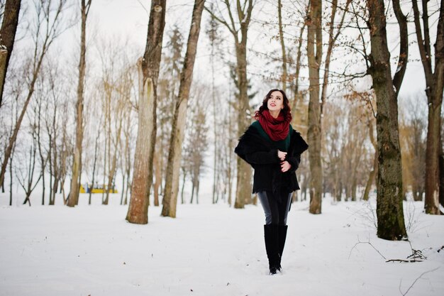 Brunette girl in green sweater coat and red scarf outdoor on evening winter day