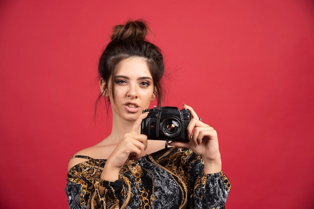無料写真 プロのデジタル一眼レフカメラを保持し、フォトセッションを行っているブルネットの少女。