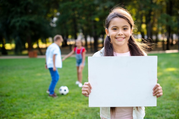 Ragazza castana che tiene insegna in bianco