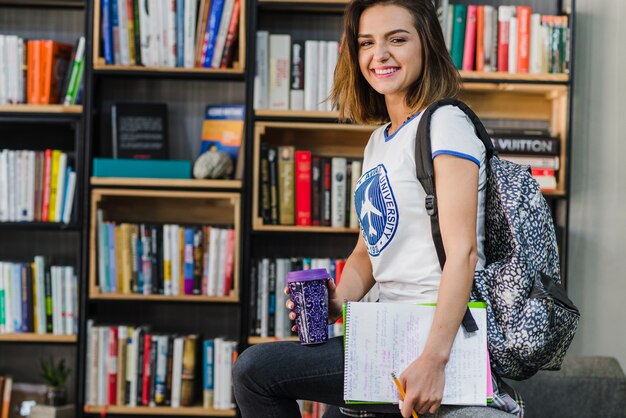 Brunette girl holding notepads cup sitting smiling