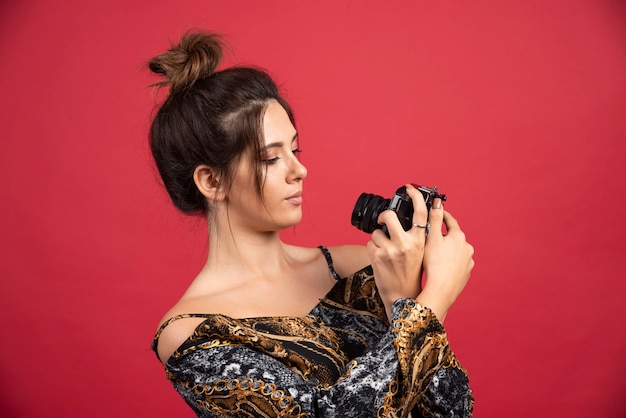 Brunette girl holding a professional dslr camera and takes her disappointed selfies.