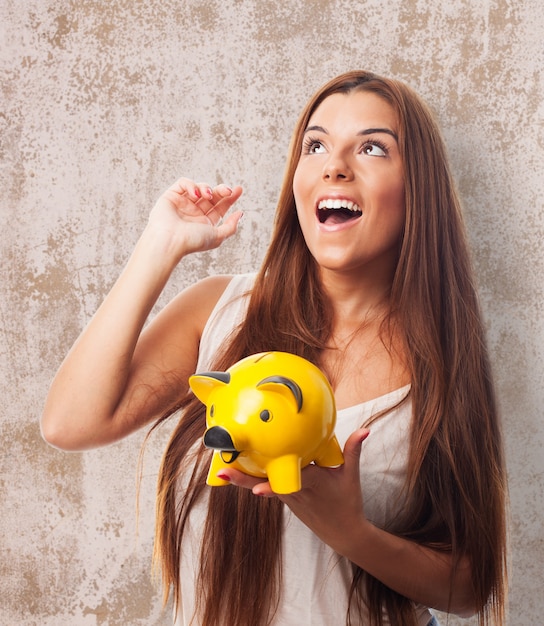 Brunette girl holding yellow moneybox