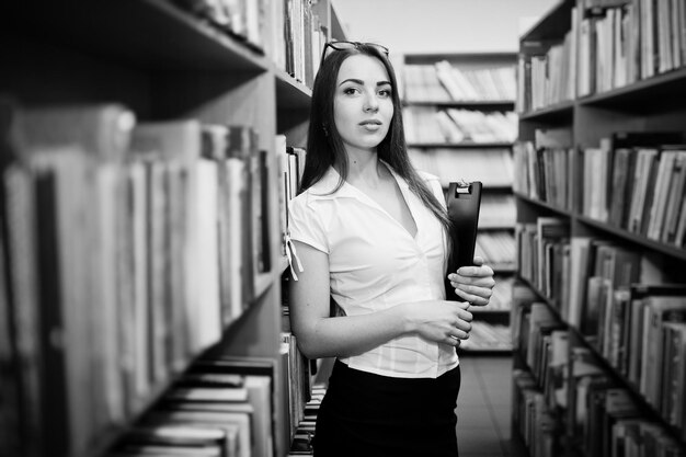 Brunette girl at library with folder of documents wear on white blouse and black mini skirt Sexy business woman or teacher concept Black and white photo