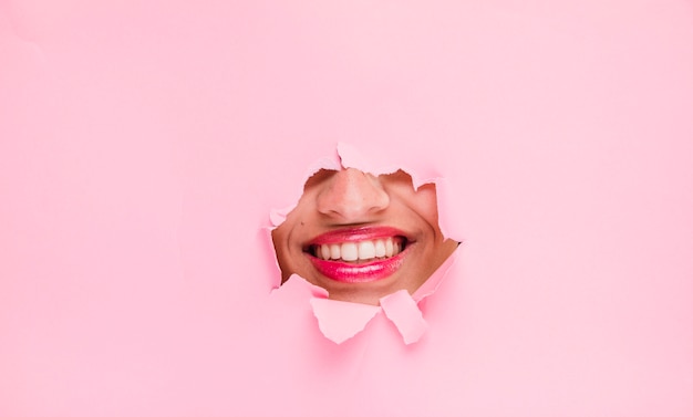 Brunette girl posing through a paper hole