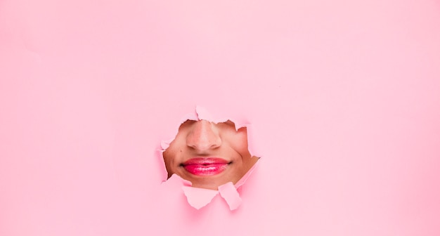 Brunette girl posing through a paper hole