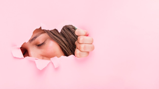 Free photo brunette girl posing through a paper hole