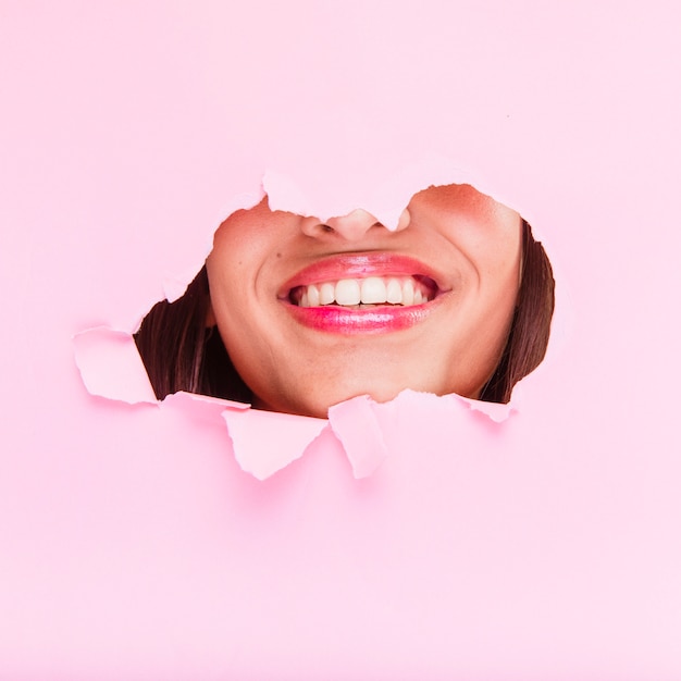 Brunette girl posing through a paper hole
