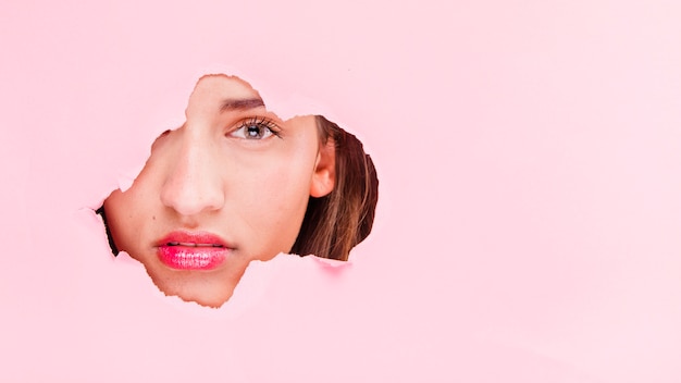 Brunette girl posing through a paper hole