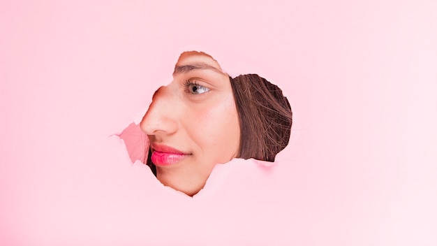 Brunette girl posing through a paper hole