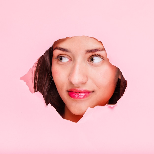 Brunette girl posing through a paper hole