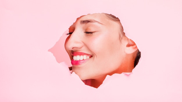 Brunette girl posing through a paper hole