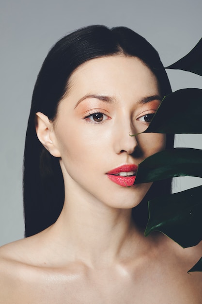 Brunette girl posing with exotic leaves