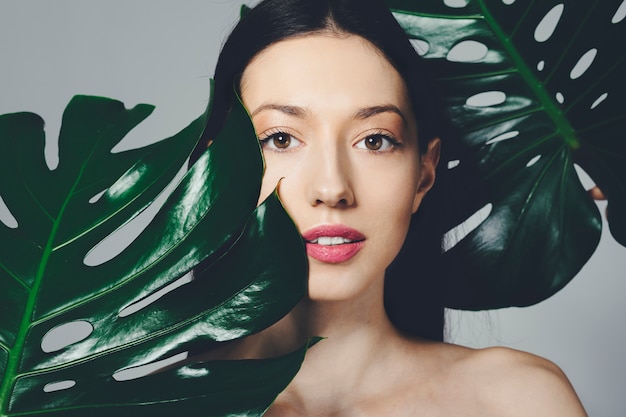 Brunette girl posing with exotic leaves